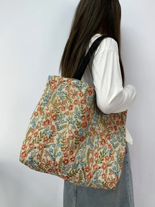Detail of floral tapestry tote bag featuring Monet-style blue sunflower and red patterns
