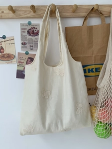 Détail d'un grand sac cabas en toile blanche orné d'une broderie papillon 3D raffinée