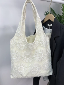 Détail de la broderie de tournesols sur le sac en toile et en maille blanc cassé