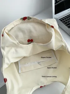 Detail of canvas tote bag interior with zipper pocket, open pouch and cherry embroidery