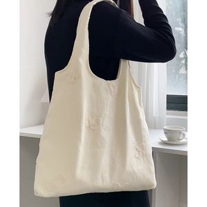 Détail d'une broderie papillon délicate sur un sac fourre-tout en toile blanc crème