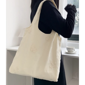 Détail de la broderie papillon 3D sur le sac fourre-tout en toile blanc crème
