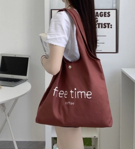 Detailed close-up of dark red canvas tote bag showing free time coffee print and gold buckle