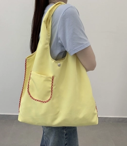 Close-up of yellow canvas tote bag with red gingham trim and silver snap button