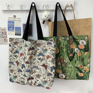Detail of woven tapestry tote bags with floral patterns and black canvas shoulder straps