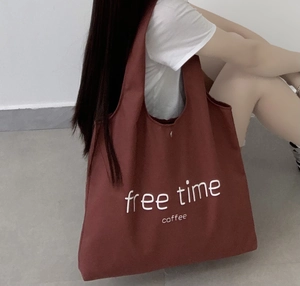 Detail of burgundy canvas tote bag featuring white free time coffee artistic lettering