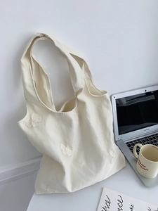 Détail de la broderie sur un sac en toile crème avec patchs papillon 3D et bandoulière large