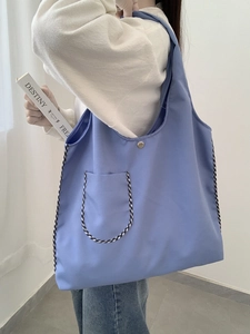 Detail of light blue canvas tote bag with checkered trim and silver magnetic snap closure