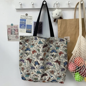 Detail of floral canvas tote bag featuring butterfly patterns hung on a wooden wall hook