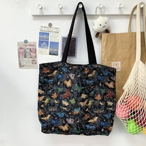 Detail of vintage butterfly embroidery on large black tote bag in lifestyle setting