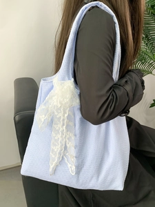 Detailed close-up of blue plaid canvas tote featuring a white floral lace bow decoration