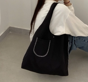 Close-up of large black canvas tote bag with woven trim pocket worn by model