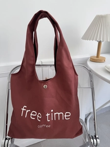 Detail of red canvas tote bag featuring white free time text on a minimalist chair