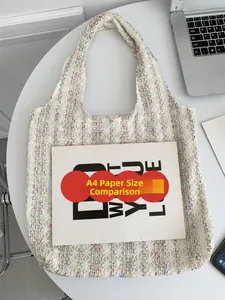 Size comparison of white knit tote bag with A4 paper on desk for scale and volume reference