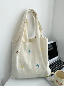 Close-up of colorful balloon dog embroidery on off-white canvas tote bag with laptop
