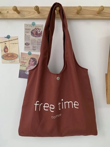Large brick red canvas tote bag with free time coffee print hanging on a wooden hook