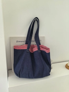 Gros plan sur le sac cabas en jean bleu foncé avec bordure à carreaux vichy rouge et blanc