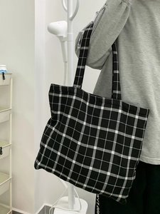 Vue latérale d'un grand sac cabas en toile à damier noir et blanc sur modèle