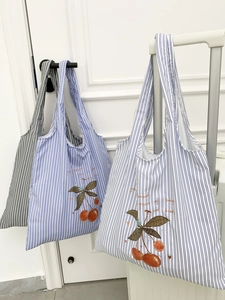 Detail of striped canvas tote bags featuring red cherry prints and decorative calligraphy