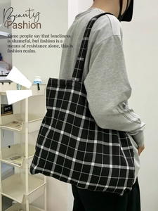 Détail du cabas en toile à damier noir et blanc avec une large bandoulière souple