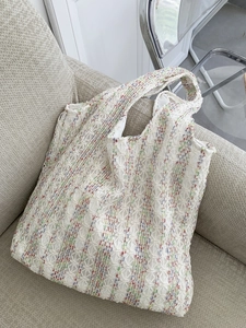 Close-up of knit tote bag with colorful floral patterns on a gray textured sofa