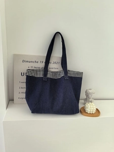 Détail d'un cabas en denim bleu foncé avec bordure vichy dans un décor intérieur minimaliste
