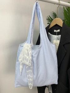 Detail of blue gingham canvas tote bag with a large white lace bow on metal hanger