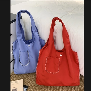 Detail of red and blue nylon tote bags with front pockets and silver magnetic snaps