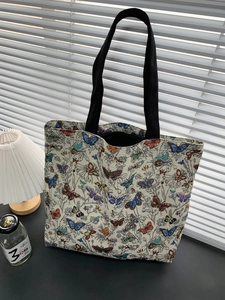 Detail view of large tote bag with colorful butterfly print and black shoulder straps