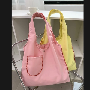 Detail of pink and yellow nylon tote bags with red checkered pockets on a metal chair