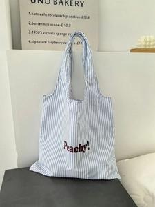 Detail of blue and white striped canvas tote bag featuring brown Peachy! text embroidery