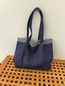 Détail du cabas en denim bleu foncé avec bordure à carreaux noirs et blancs sur banc