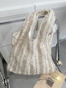 Close-up of multicolor woven knit tote bag texture on a modern transparent chair