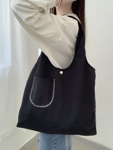 Minimalist black canvas tote bag with checkered trim pocket and gold snap button closure