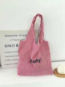 Detail of red gingham canvas tote bag with black Peachy text in a stylish home setting