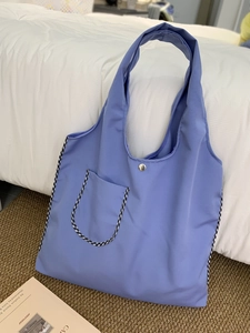 Detailed close-up of blue canvas tote bag featuring a silver metal button and checkered pocket