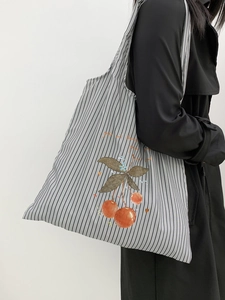 Detail of striped canvas tote bag featuring a red cherry print and spacious interior