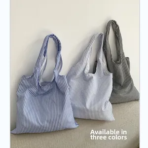Vue détaillée des sacs cabas en toile rayée en trois coloris : bleu, bleu clair et gris