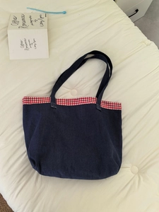 Détail du sac cabas en denim bleu avec bordure vichy rouge et blanc et anses solides