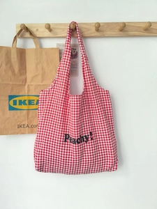 Detail of red and white checkered canvas tote bag with black Peachy text print