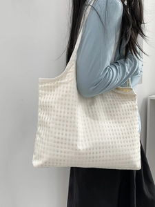 Detailed macro of checkered fabric texture on a large minimalist white tote bag