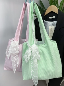 Detail of canvas tote bags featuring large lace bows and pastel striped textured fabric