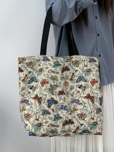 Detail of floral jacquard tote bag with butterfly patterns and black canvas handles