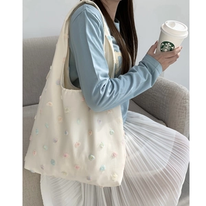 Detail view of cream canvas tote bag featuring multi-colored 3D floral embroidery appliques