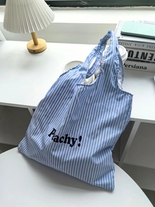 Close-up of blue and white striped tote bag with Peachy letter print and sturdy handles