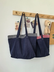 Vue détaillée du grand sac cabas en denim avec bords à carreaux sur un crochet en bois