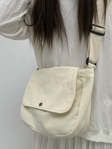 Minimalist cream canvas crossbody bag with vintage buckle shown on a model