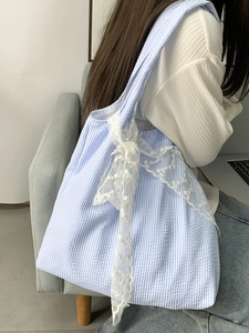 Detailed shot of blue and white striped tote bag with white lace bow and seersucker texture