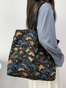 Detailed view of large tote bag featuring colorful butterfly patterns and black strap