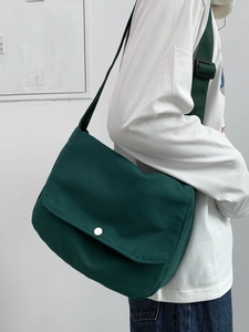 Detail of dark green canvas messenger bag with silver metal buckle on a shoulder strap